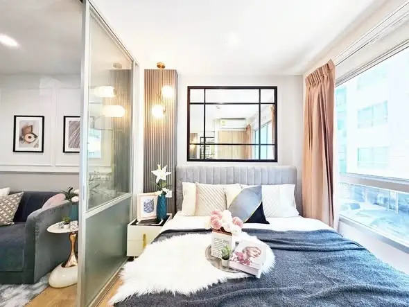 Chic modern bedroom with large windows and stylish decor in urban apartment.