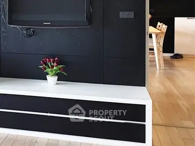 Modern living room with sleek black and white furniture and wall-mounted TV
