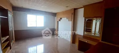 Spacious empty room with wooden built-in shelves and large window.
