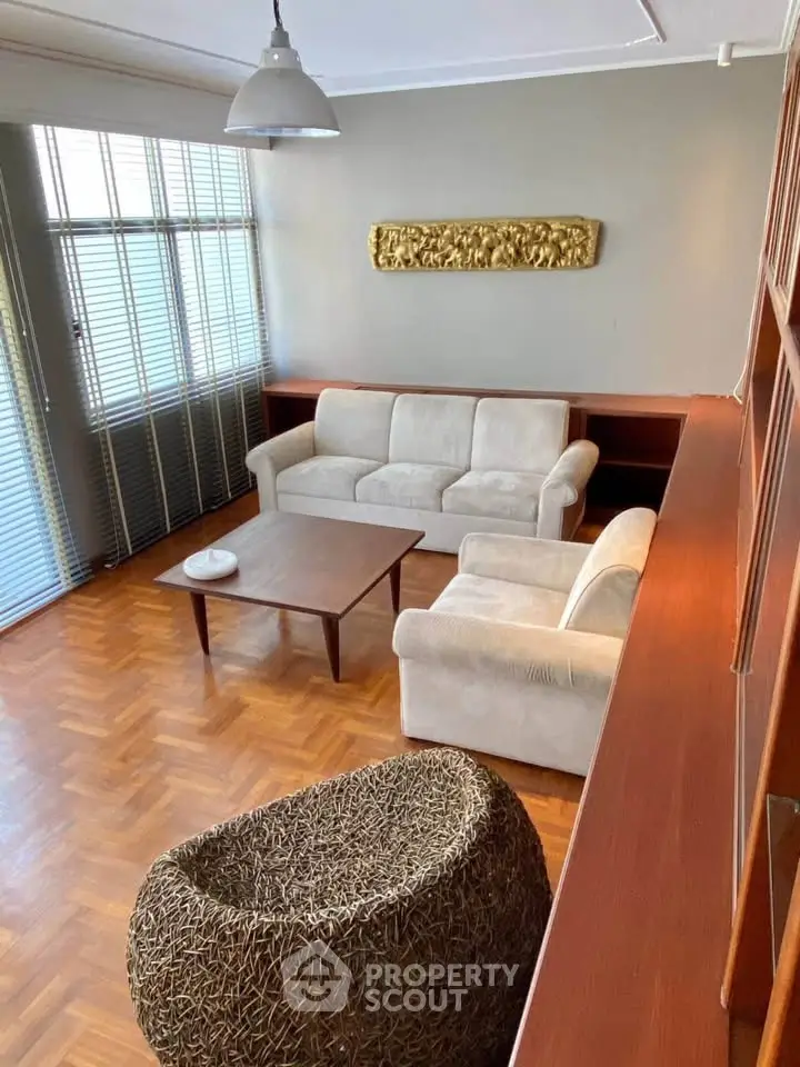 Charming living room with parquet flooring and cozy seating in a stylish apartment.