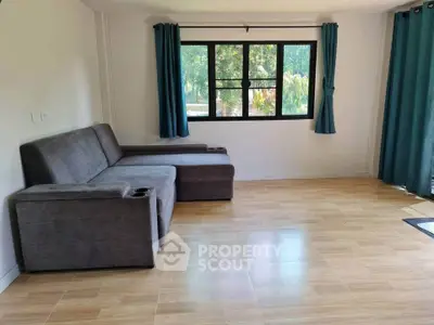 Spacious living room with modern gray sofa and large window offering garden views.