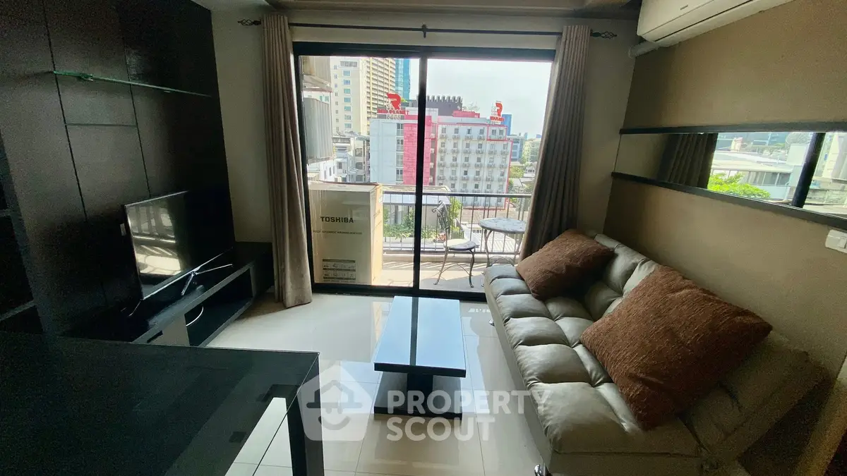 Modern living room with city view, cozy sofa, and sleek TV setup in urban apartment.