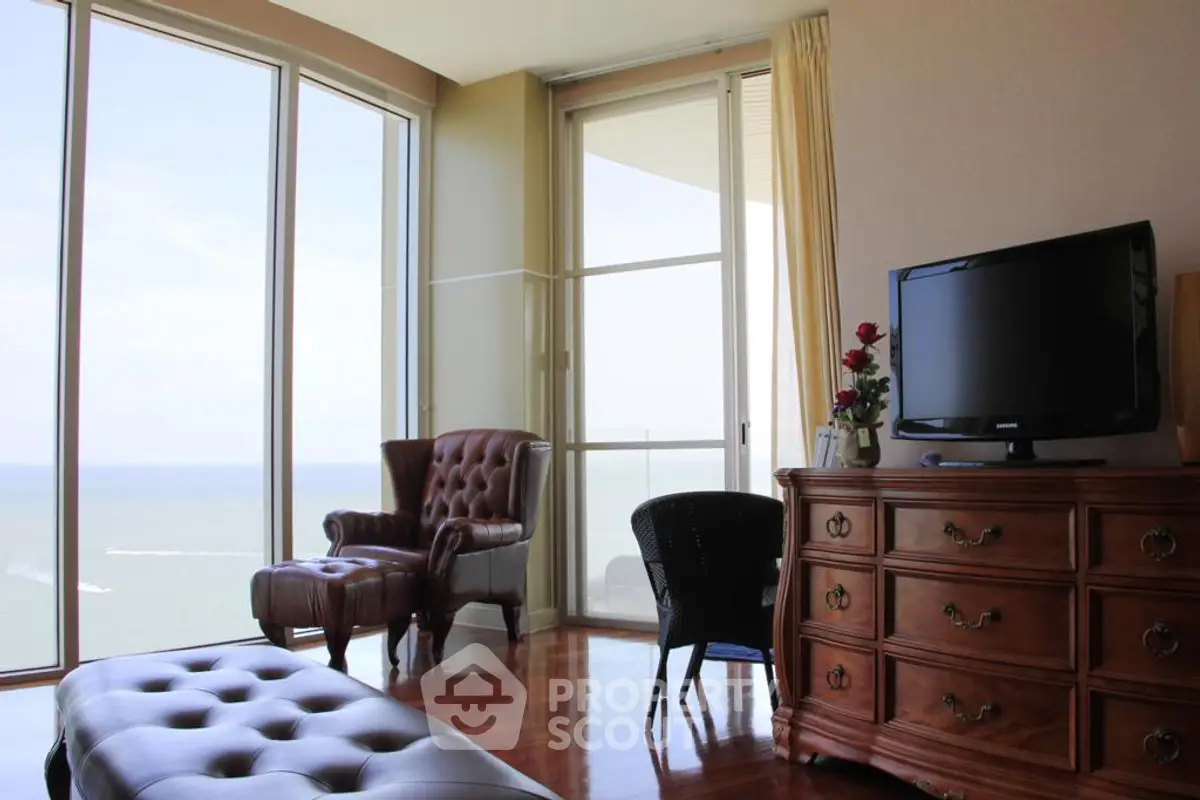 Luxurious living room with ocean view, elegant furniture, and floor-to-ceiling windows.