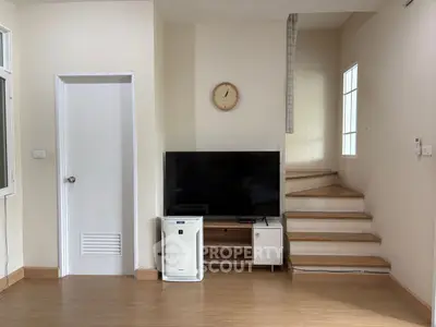 Modern living room with TV and wooden staircase, perfect for cozy family gatherings.