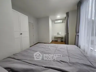 Spacious bedroom with modern decor and large windows for natural light.