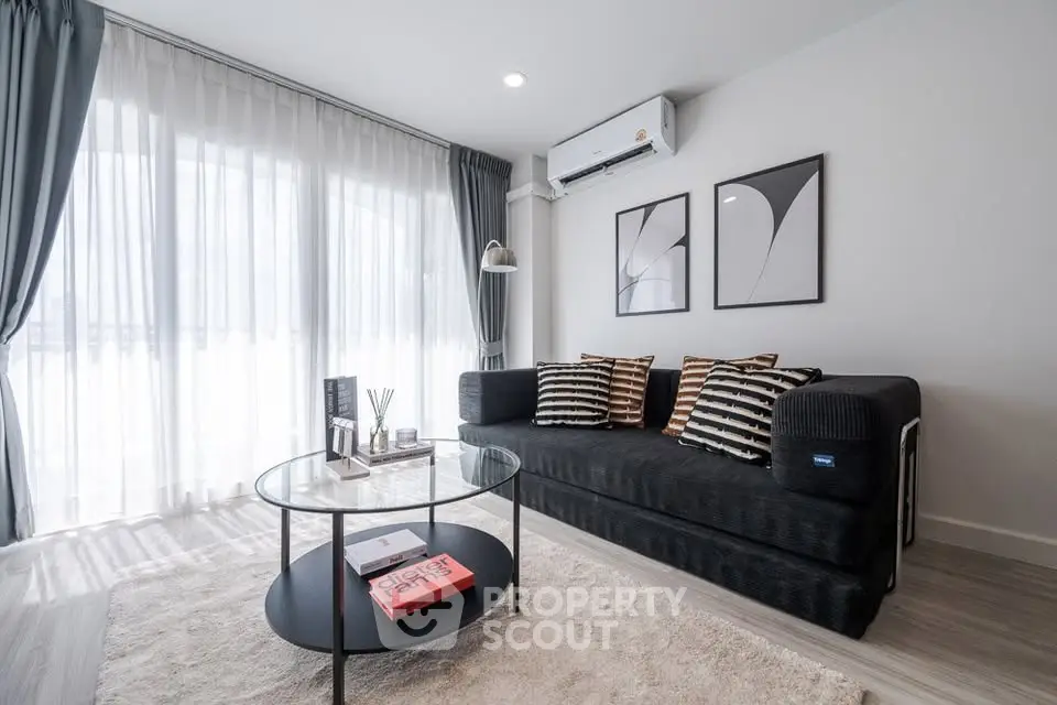 Modern living room with stylish decor, large windows, and cozy seating area.