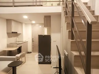 Modern loft apartment with stylish kitchen and cozy living area, featuring a sleek staircase and contemporary design.