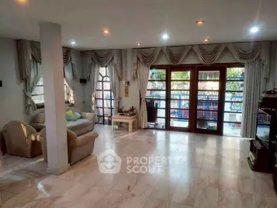 Spacious living room with elegant drapes and large windows opening to a balcony.