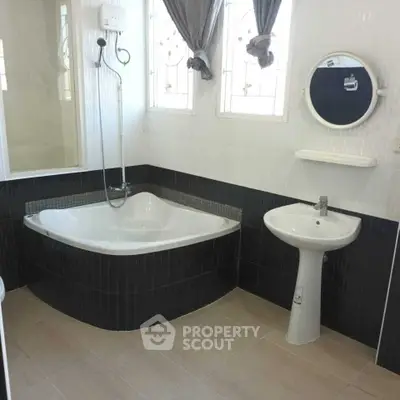 Modern bathroom with corner bathtub and elegant fixtures in a stylish real estate property.