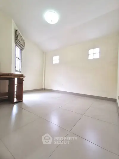 Spacious empty room with tiled flooring and natural light