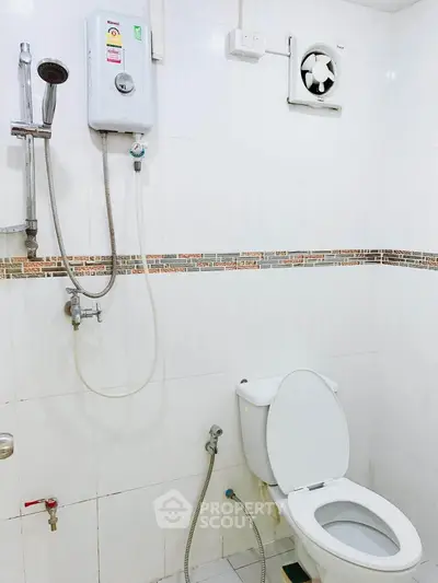 Modern bathroom with shower and toilet in a clean white tiled setting.