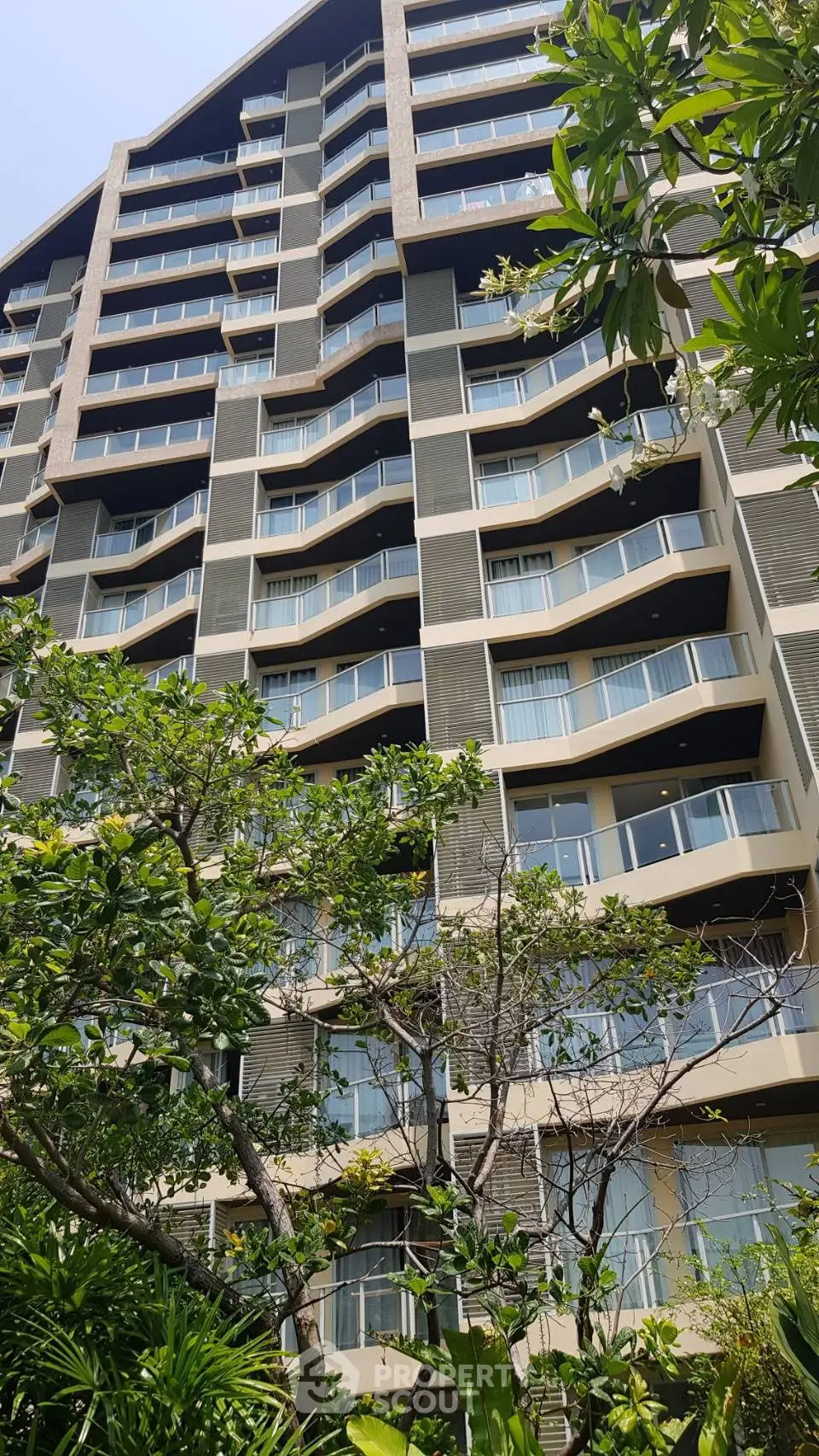 Modern high-rise building with unique balcony design and lush greenery