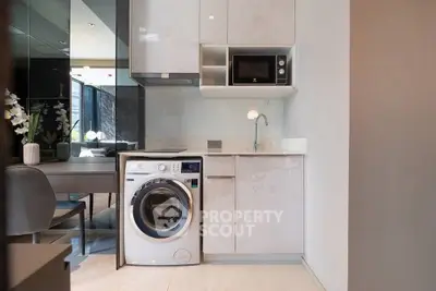 Modern kitchen with washing machine and microwave in sleek apartment