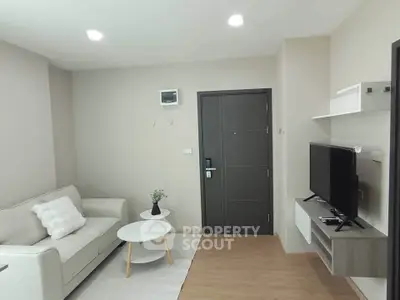 Modern living room with sleek furniture and neutral tones, featuring a cozy sofa and flat-screen TV.