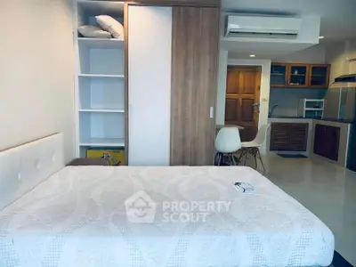 Modern studio apartment with cozy bed and compact kitchen area