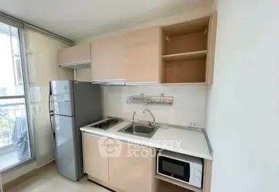 Modern kitchen with sleek cabinetry, stainless steel fridge, and microwave in a bright apartment.