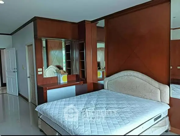 Spacious bedroom with elegant wooden accents and a comfortable bed, perfect for relaxation.