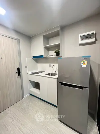 Modern compact kitchen with sleek design and stainless steel fridge in a stylish apartment.