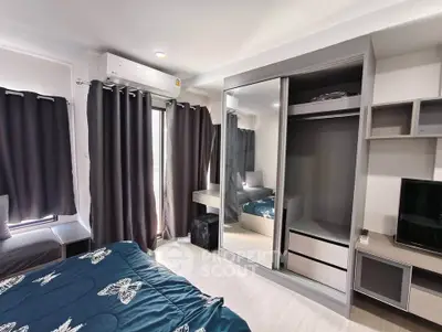 Modern bedroom with stylish decor, large mirrored wardrobe, and natural light from window.