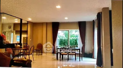 Spacious living room with dining area and large windows overlooking greenery.