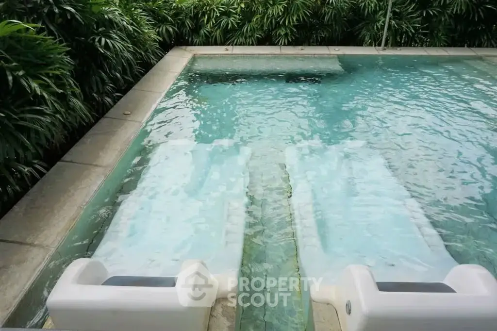 Luxurious outdoor pool with lush greenery, perfect for relaxation and leisure in a serene environment.
