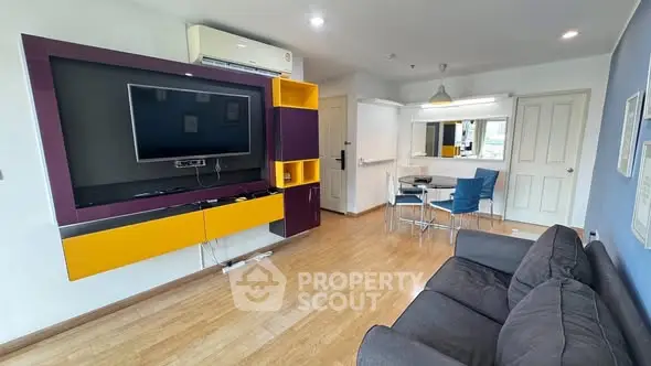 Modern living room with vibrant TV unit and cozy seating area in a stylish apartment.