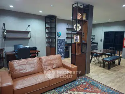 Stylish living room with leather sofa, modern shelving, and cozy workspace in open layout.