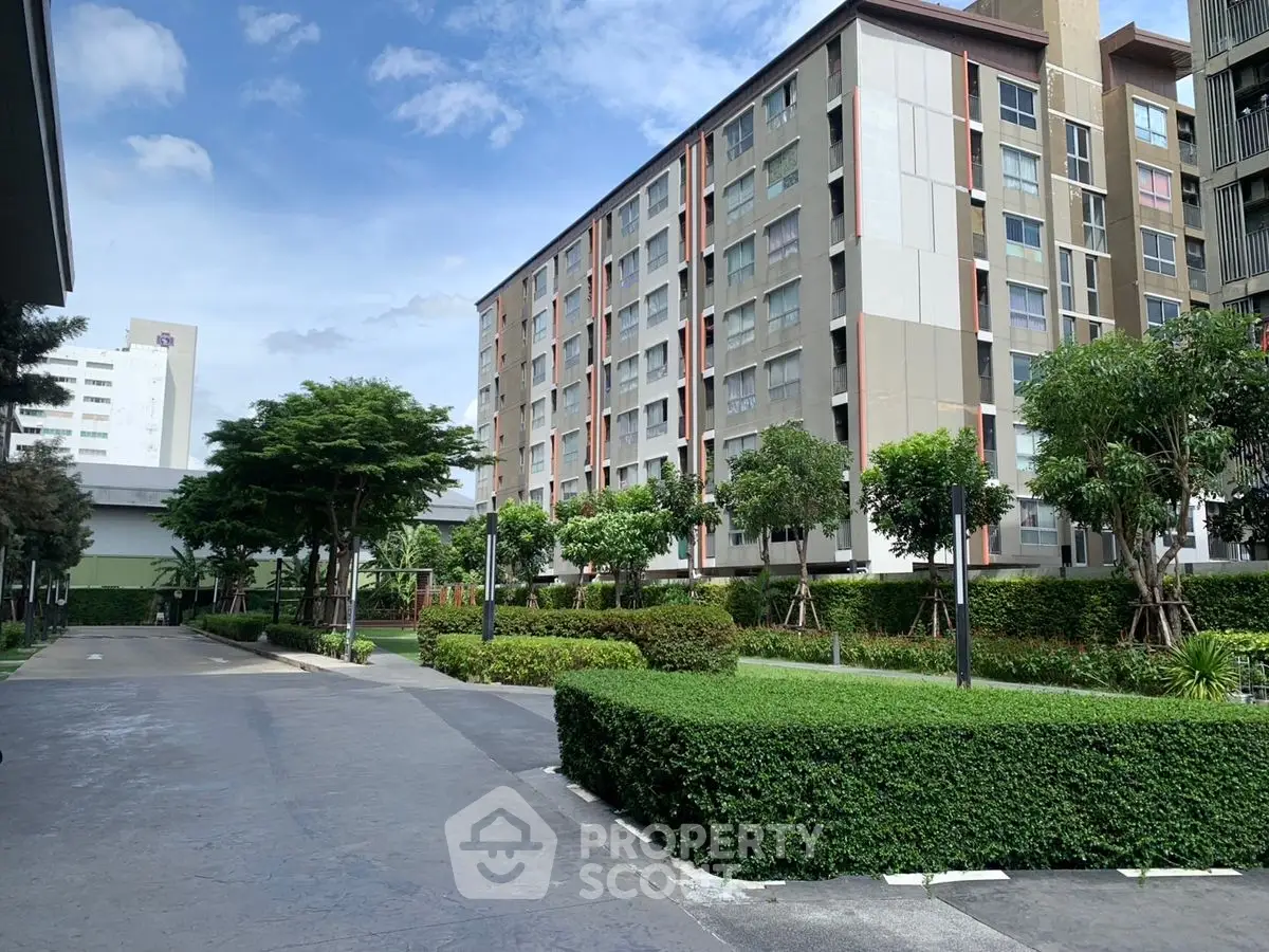 Modern apartment building with lush greenery and clear blue sky.