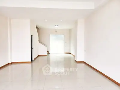 Spacious empty room with glossy tile flooring and bright natural light.