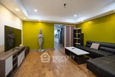 Spacious living room with modern decor and unique statue, featuring a sleek black sofa and flat-screen TV.