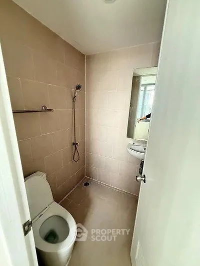 Compact bathroom with modern fixtures and neutral tiles, ideal for urban living.