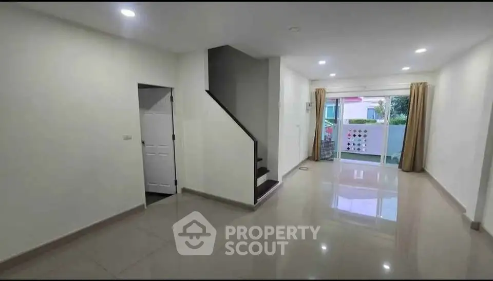 Spacious modern living room with sleek staircase and large windows for natural light.