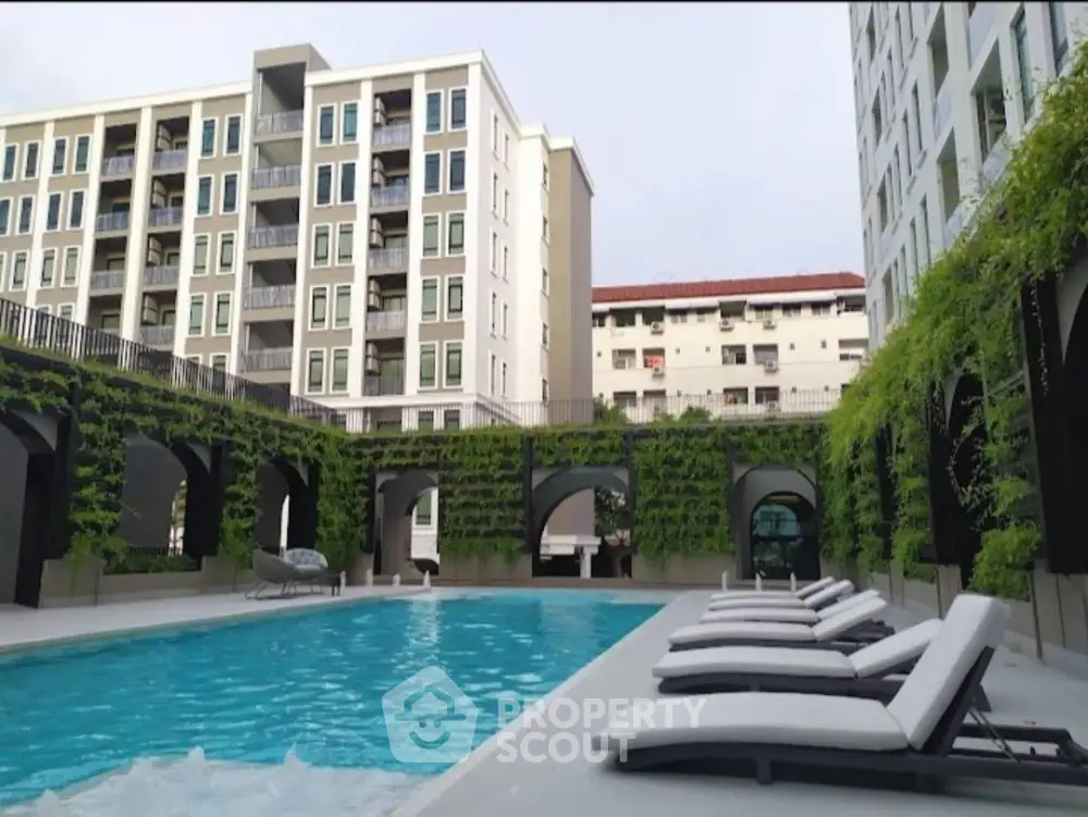 Luxurious apartment complex with modern pool and stylish lounge chairs, perfect for relaxation.