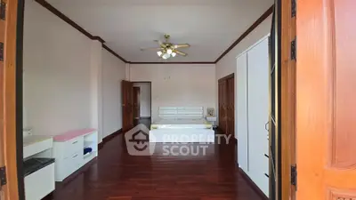 Spacious bedroom with wooden flooring and ceiling fan