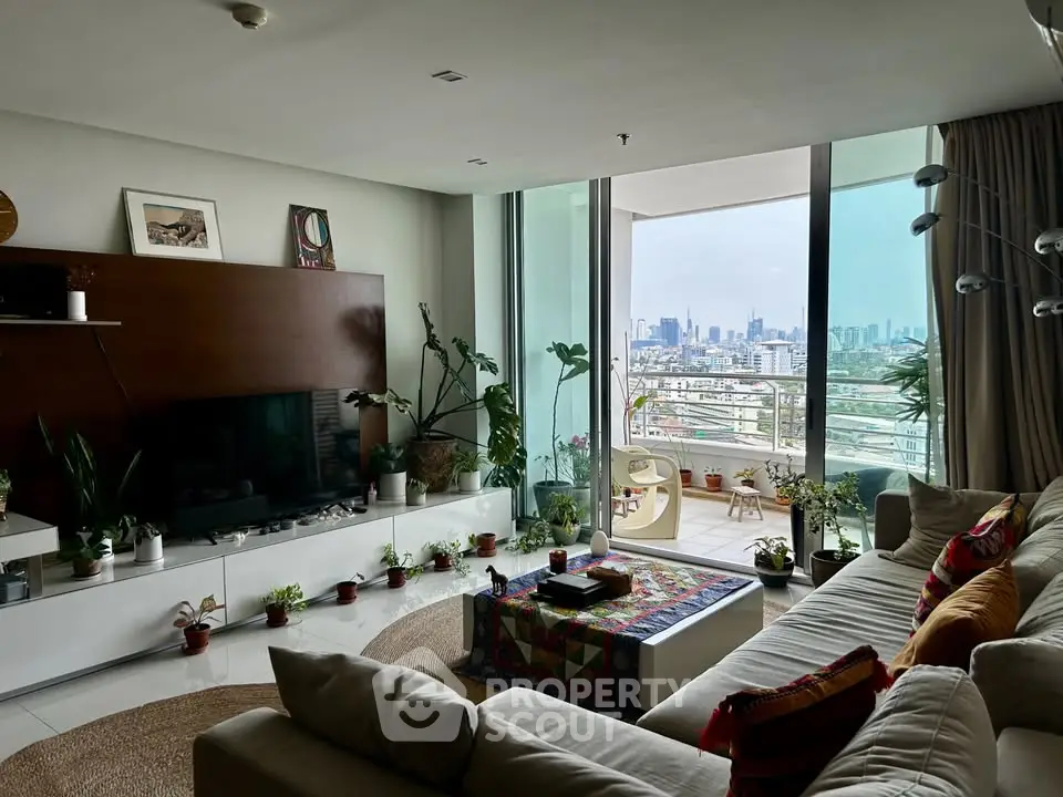 Spacious living room with city view and large balcony, featuring modern decor and abundant natural light.