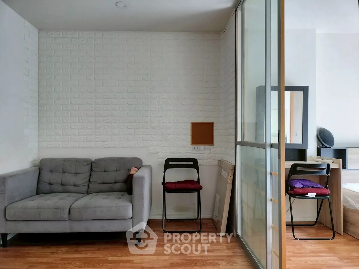 Modern apartment interior with cozy living area and stylish bedroom separated by sliding glass doors.