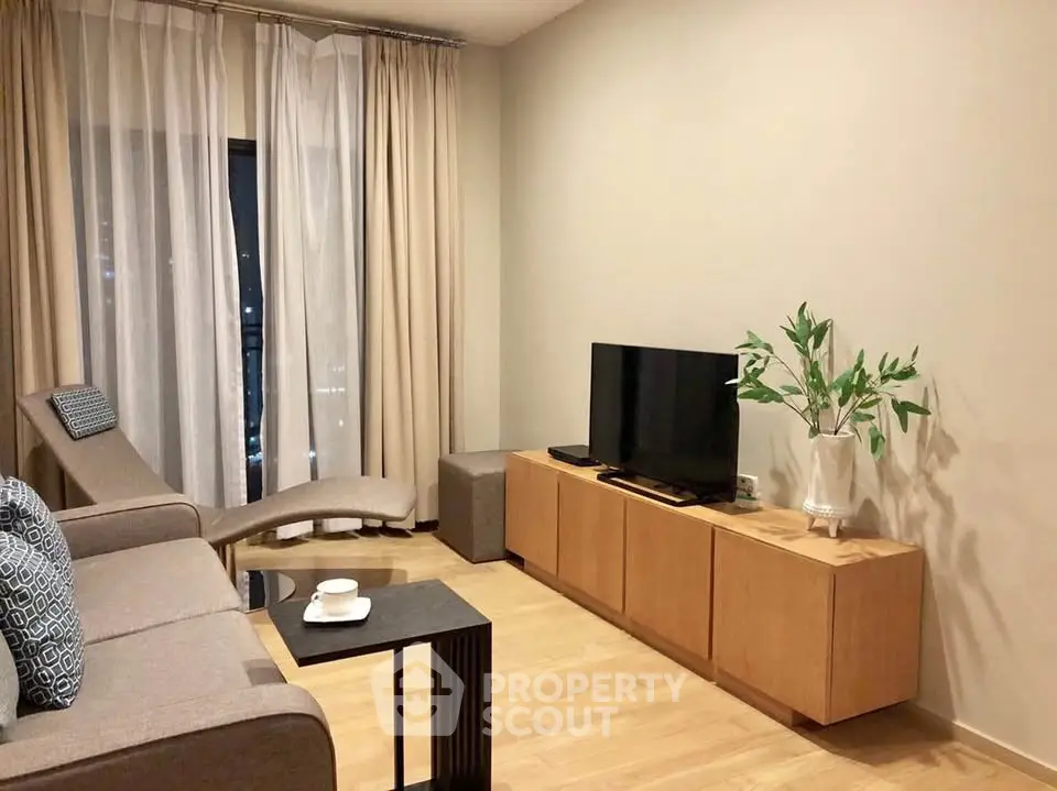 Modern living room with stylish furniture and natural light, featuring a sleek TV stand and cozy seating area.
