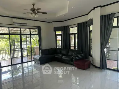 Spacious living room with large windows and balcony access, featuring modern furniture and elegant curtains.