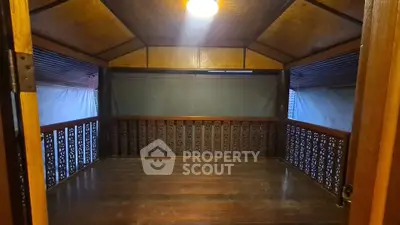 Charming wooden balcony with intricate railing design and warm lighting, perfect for relaxation.