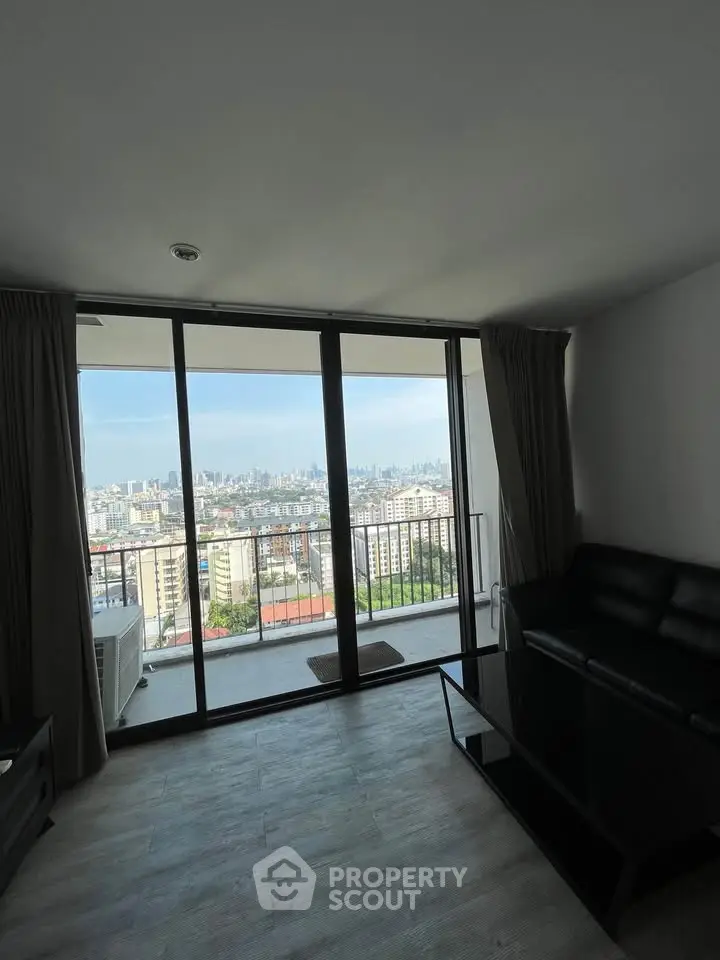 Spacious living room with stunning city view from large glass doors and balcony.