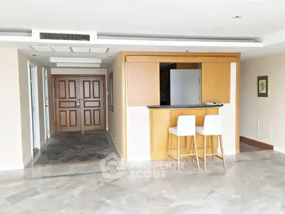 Spacious open-plan living area with modern bar counter and elegant flooring.