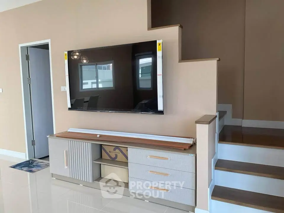 Modern living room with stylish TV unit and staircase in contemporary home