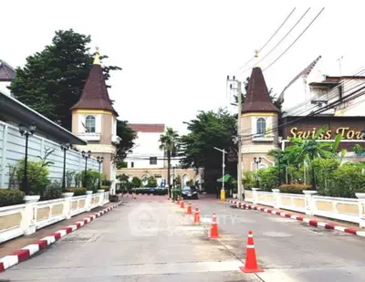 Charming European-style building entrance with twin towers and lush greenery.