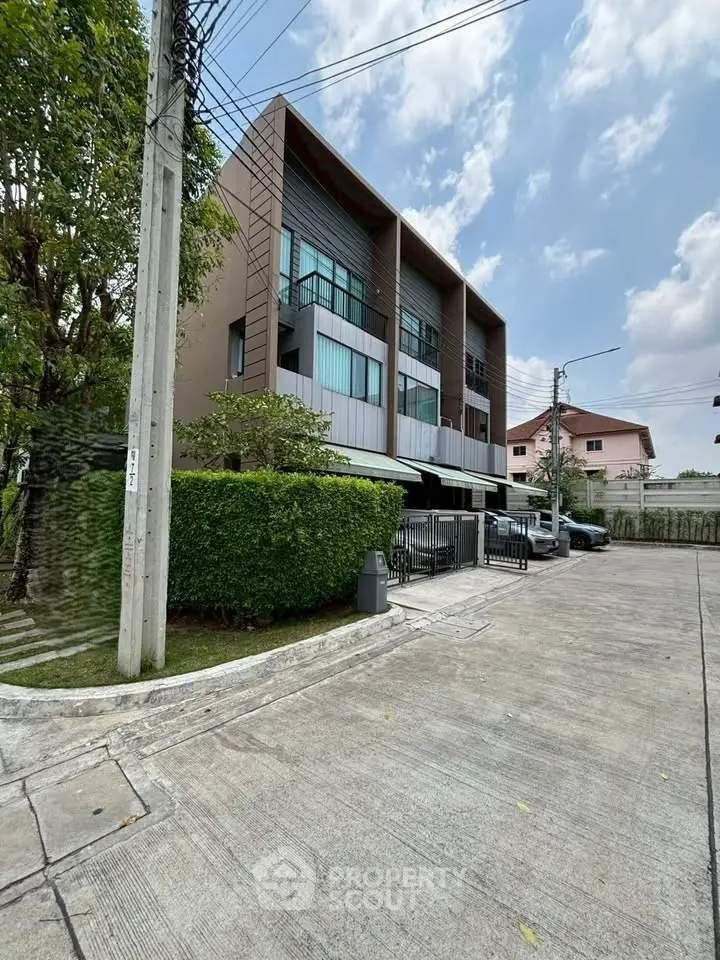 Modern townhouse exterior with sleek design and lush greenery in a suburban neighborhood.