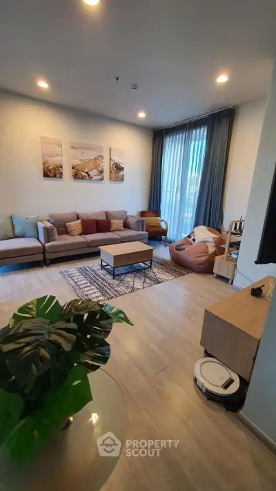 Modern living room with stylish decor, cozy seating, and natural light from large windows.
