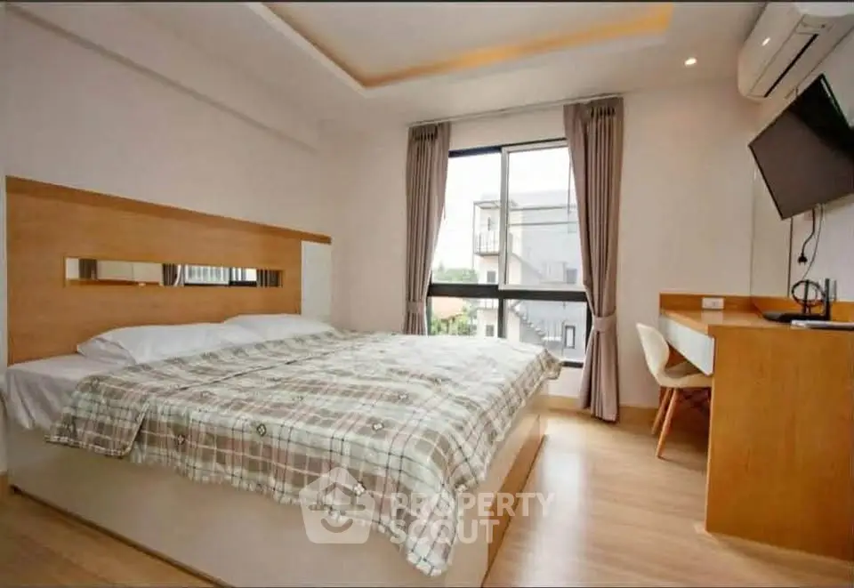 Modern bedroom with large window and stylish decor in a cozy apartment.