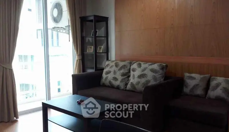 Cozy living room with modern sofa and natural light from large window.