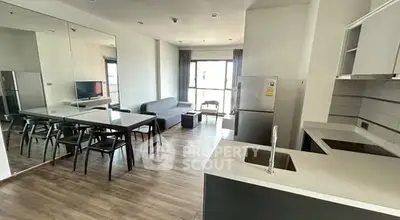 Modern open-plan living room with kitchen and dining area, featuring sleek design and natural light.