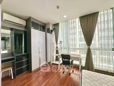 Spacious bedroom with modern furniture and large windows in a high-rise apartment.