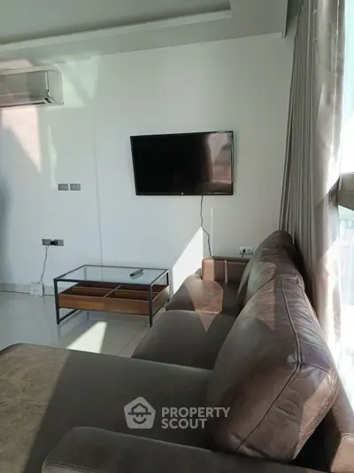 Modern living room with sleek sofa and wall-mounted TV, bathed in natural light.